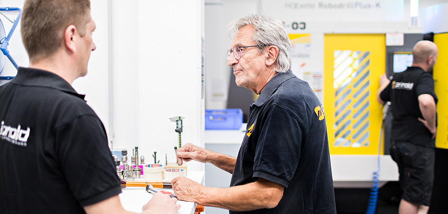 Zwei Priomold Mitarbeiter unterhalten sich in einer Werkstatt Zwei Priomold Mitarbeiter unterhalten sich in einer Werkstatt