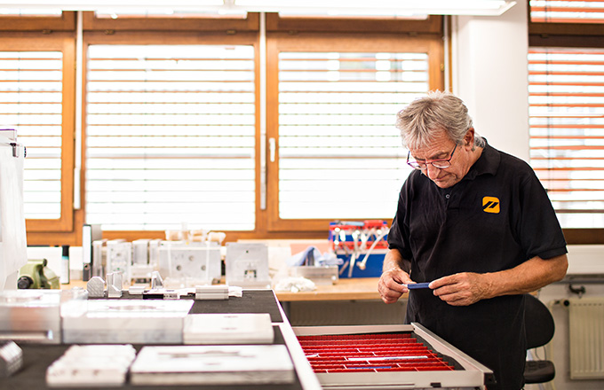 Priomold Mitarbeiter mit Bauteil in der Hand Priomold Mitarbeiter mit Bauteil in der Hand